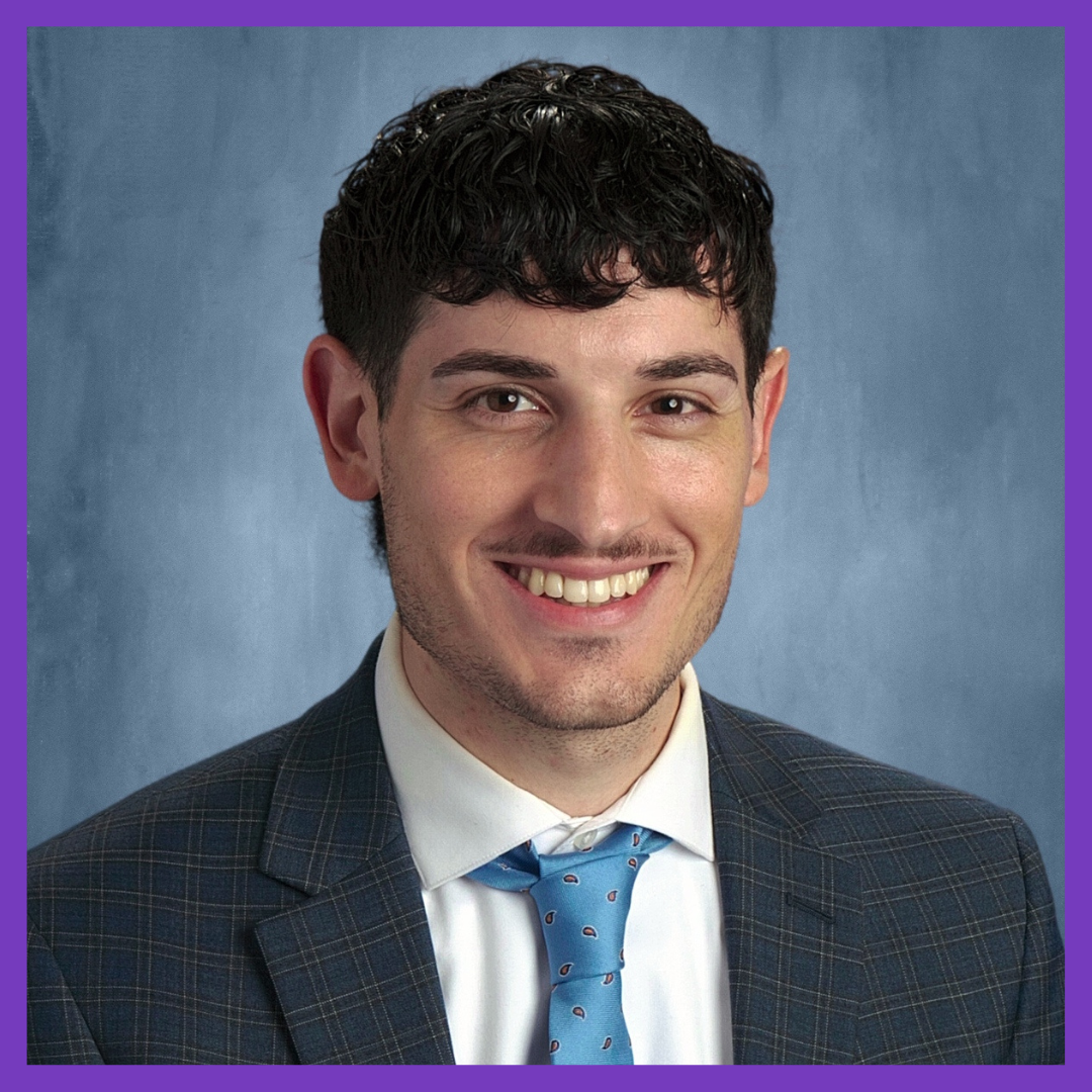 Photo of man wearing suit with light blue tie, against a blue background